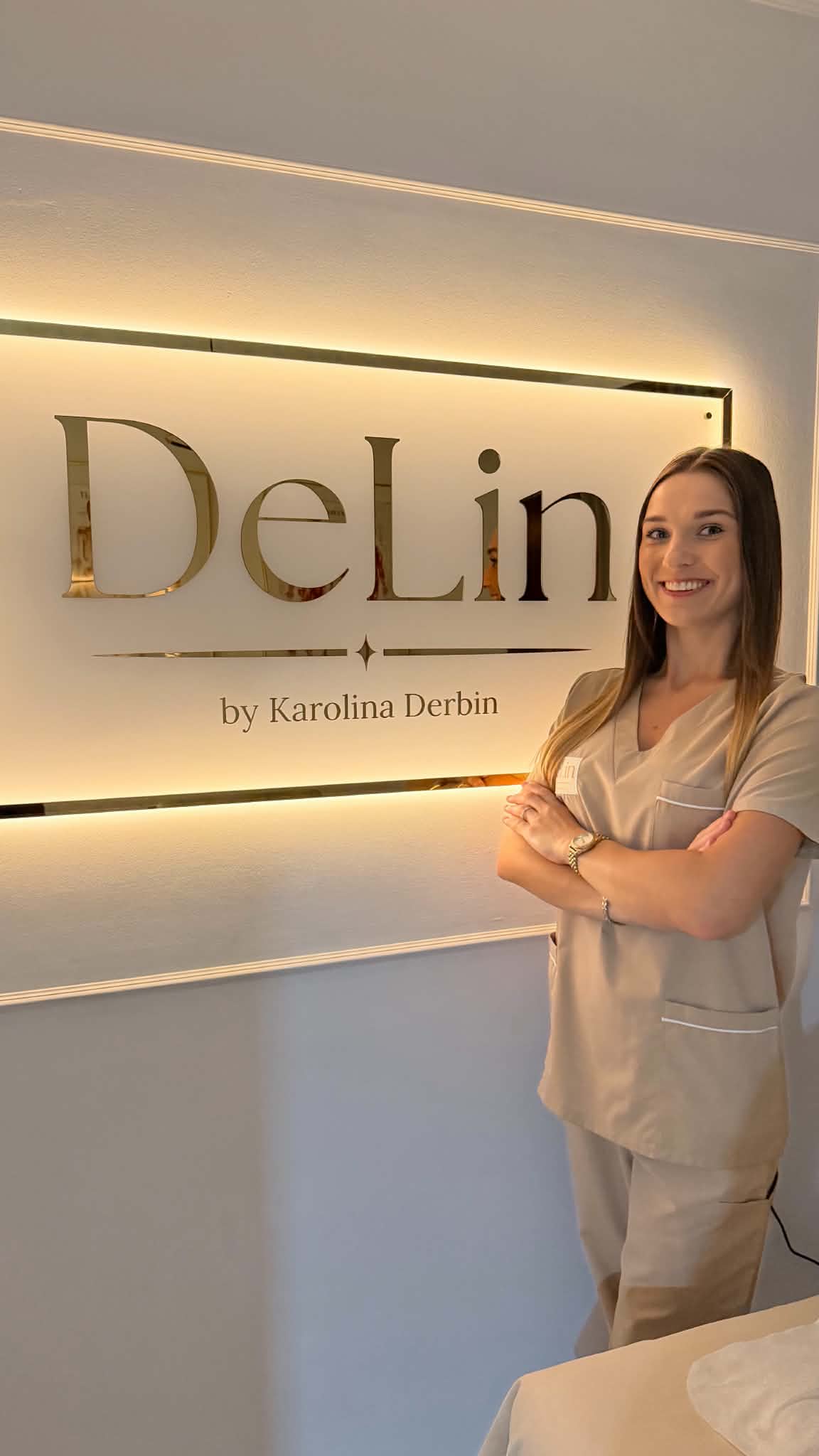 Karolina Derbin przy podświetlanym szyldzie DeLin w gabinecie masażu w Warszawie